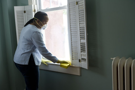 woman wearing mask and gloves cleaning inside her house